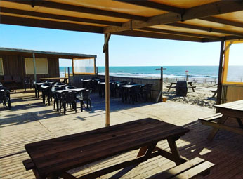 Bar restaurant avec terrasse en bois qui donne directement sur la plage